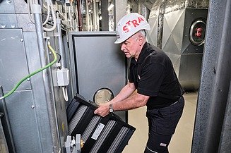 Maximum availability Photo of an employee in a helmet replacing the filter of a ventilation system
