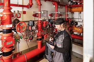 Warranty management Photo of employee standing at a sprinkler system and looking into a tablet