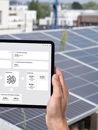Foto von einem Tablet mit Gebäudeinformationen vor einer Photovoltaik-Anlage