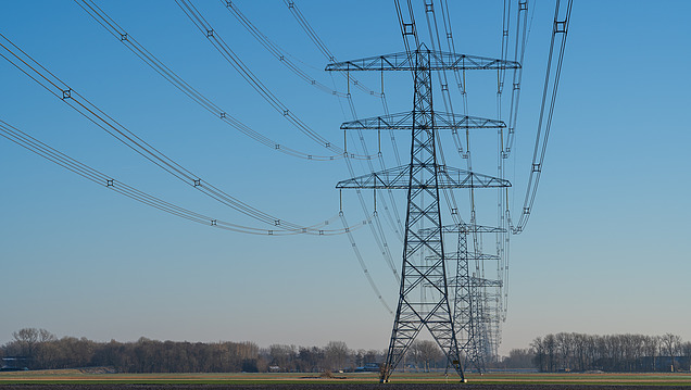 Bild einer Aneinanderreihung von Stromtrassen vor blauem Himmel