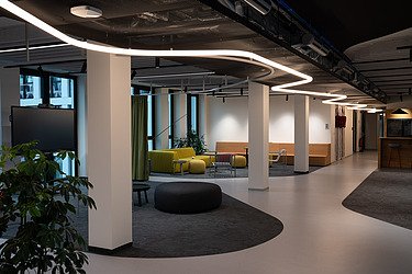 Modernes Großraumbüro im Industriedesign mit Sitzlounges, moderne Leuchtstoffbeleuchtung.