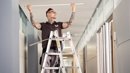 Picture of a janitor changing a ceiling light