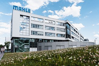 Photo of a wide glass building with letters ´MAHLE´