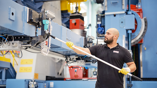 Picture of a man cleaning a machine with a wiper