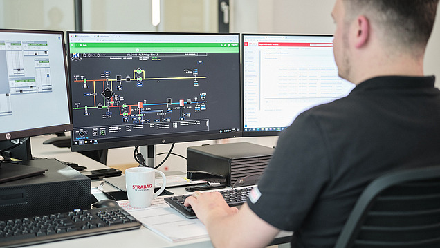 Photo of an employee at a desk looking at three screens