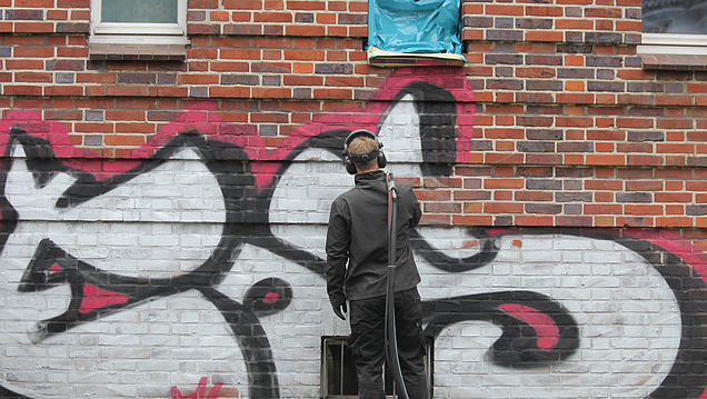 Picture of a person removing graffiti from a wall