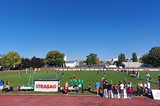 Photo of a football field with some people and a STRABAG flag