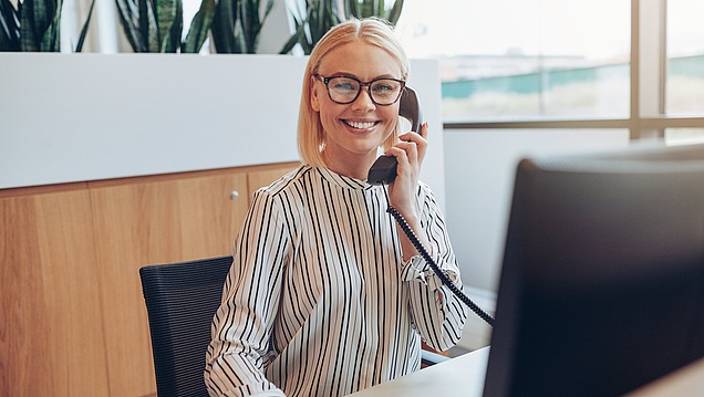 Picture of a woman sitting at reception and talking on the phone