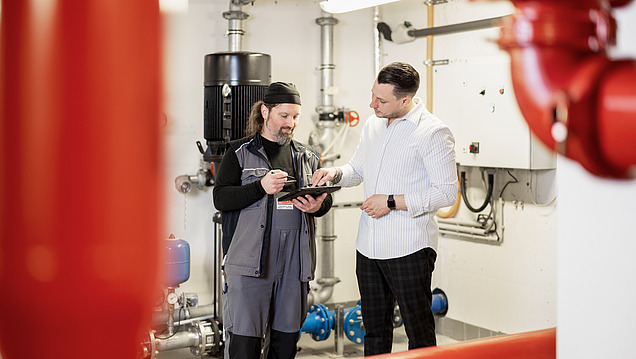 Photo of a property manager and a technician looking at a tablet in a technical room