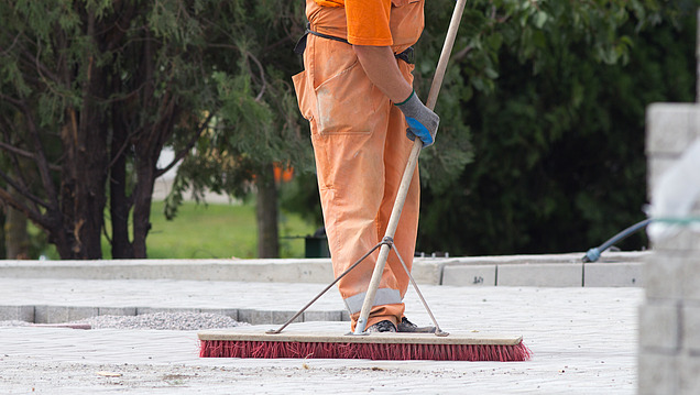 Bild von einem Mann, der mit einem Besen auf einer Baustelle fegt