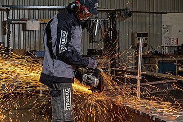 Picture of man in protective clothing with saw spraying sparks