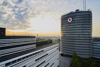 Foto von einem Gebäude mit Vodafone-Logo, vor einem Sonnenuntergang mit Wolken