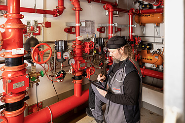 Photo of employee standing at a sprinkler system and looking into a tablet