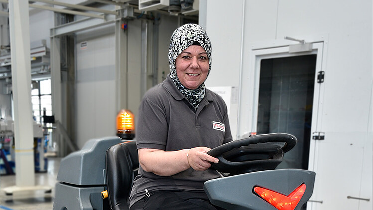 Picture of a woman driving a ride-on cleaning machine